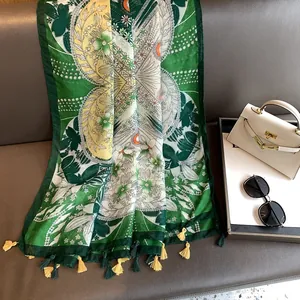 Gros plan détaillé d'un foulard en soie verte à fleurs avec pois orange et pompons