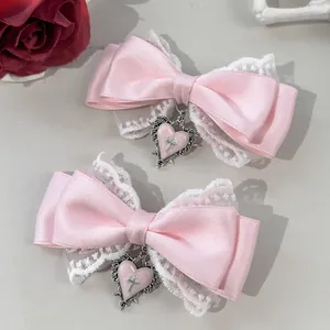 Detailansicht der rosa Satinschleifen mit weißer Spitze und silbernen Herz-Kreuz-Anhängern