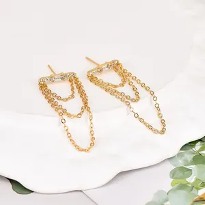 Macro shot of gold tassel drop earrings with sparkling rhinestones on textured plate