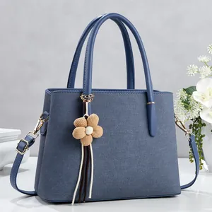 Deep blue-grey textured leather tote bag with gold hardware and floral tassel charm