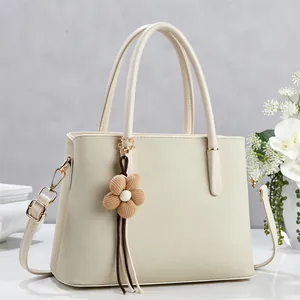 Detail of lychee pattern cream tote bag with gold buckle and floral charm decoration