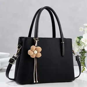 Detail of lychee pattern shoulder bag with beige flower charm and golden hardware