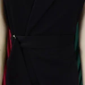 Detail of black sleeveless jumpsuit showing V-neck cross design and belted waist with metal buckle