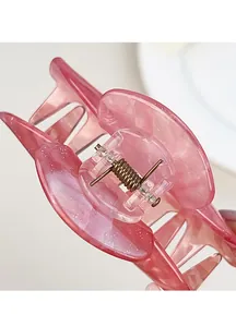 Dettaglio macro di molletta per capelli in resina marmorizzata rosa con molla in bronzo