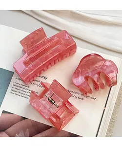 Dettaglio di un set di tre fermagli per capelli in acrilico rosa con trama perlata fine