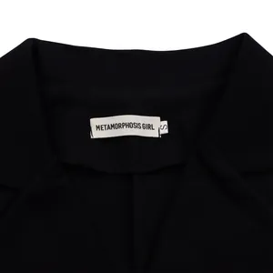 Close-up of black sleeveless jumpsuit collar with METAMORPHOSIS GIRL brand label in size S