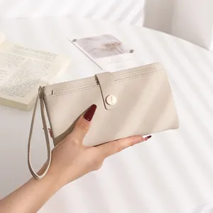 Close-up of cream litchi texture leather wallet featuring a snap buckle and wrist strap