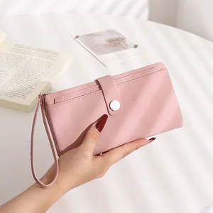 Detail of pink lychee grain long wallet featuring snap closure and wristlet strap