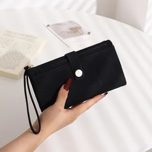 Detailed view of black litchi grain long wallet with gold buckle and wrist strap