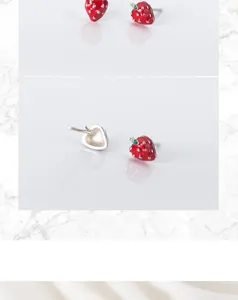 Macro view of S925 silver strawberry stud earrings with red enamel finish and leaf detail