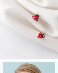 Close-up of S925 silver red strawberry stud earrings on textured white fabric