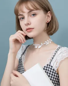 Close-up of elegant white lace leaf choker necklace and small red stud earrings