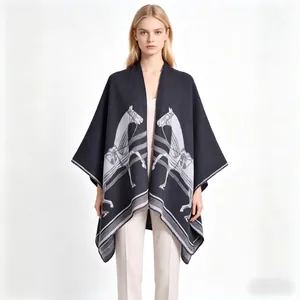 Detail showing the thick knit texture and white horse equestrian pattern on a dark poncho