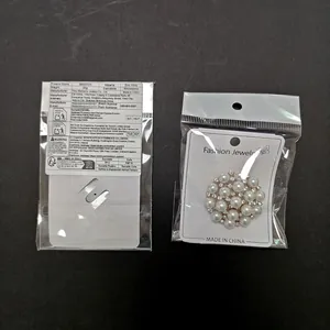 Detailed view of pearl and rhinestone brooch with packaging on black background