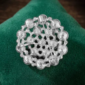 Macro view of the silver alloy snowflake brooch back with secure pin and hollow patterns
