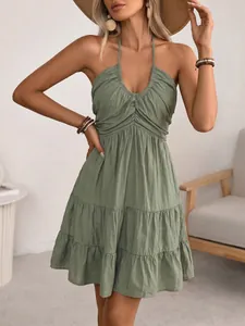 Detail of green halter neck dress featuring smocked waist and tiered ruffle skirt layer