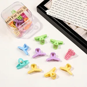 Macro detail of assorted pastel mini hair claws in a transparent storage box