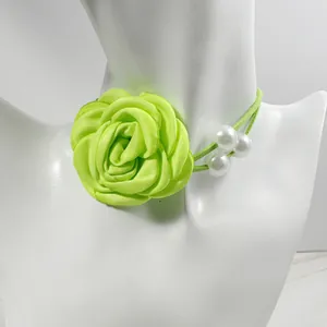 Detail of neon green fabric rose choker with delicate white pearls on a model neck