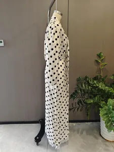Detailed side view of polka dot dress featuring elegant white lace hem and cuffs