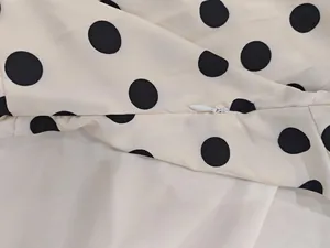 Close-up of invisible white zipper detail on black polka dot print dress fabric