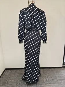 Detail of polka dot long sleeve dress featuring delicate black feather trim at the hem