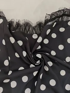 Detailed macro view of black polka dot fabric with delicate eyelash lace trim on neckline