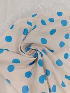Detail of cream fabric with blue polka dots and delicate white lace trim on the hem