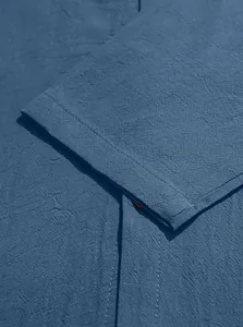 Close-up of deep blue cotton fabric texture with brown button and stitching details