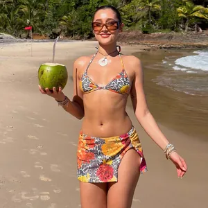 Three-piece swimsuit set with leopard floral print and wrap skirt on a sunny beach
