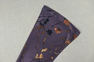 Gros plan du poignet avec imprimés de branches dorées sur tissu violet foncé et coutures