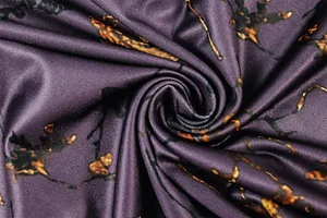 Détail du tissu brillant violet foncé avec des textures abstraites ambrées