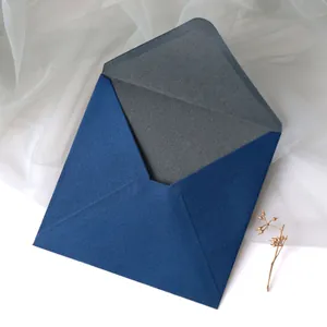 Macro shot of dark blue pearlescent paper envelope with elegant gold branch and mesh detail