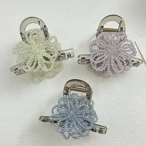 Detail of three floral hair clips in yellow, purple, and blue with beaded petals