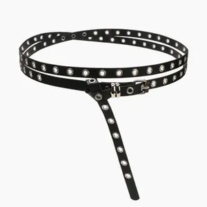 Détail d'une ceinture fine en cuir noir avec œillets métalliques argentés vintage
