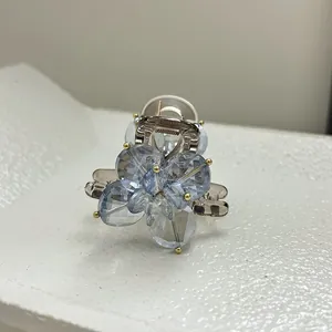 Macro detail of blue crystal flower claw clip with gold beads and amber acrylic base