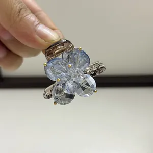 Close-up of mini flower hair claw clip with light blue crystal petals and gold accents
