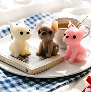 Three realistic French Bulldog shaped candles in white brown and pink on a tray