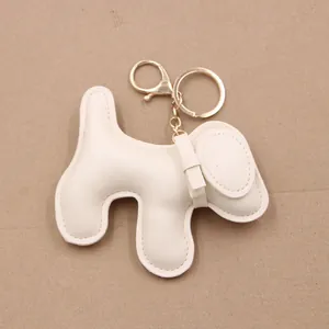 Detail showing white puppy leather keychain with gold clasp and bow tie decoration