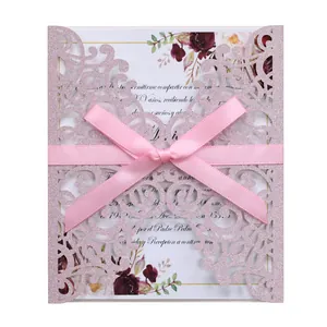 Detail of pink glitter laser-cut wedding invitation with a satin ribbon and floral pattern
