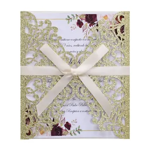 Detail of laser cut gold glitter invitation with cream ribbon bow and floral card