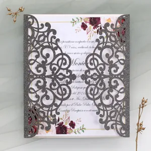 Macro detail of laser-cut silver glitter invitation with floral inner card and ribbon