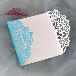 Intricate laser cut invitation cover with glittery blue vine pattern and white filigree