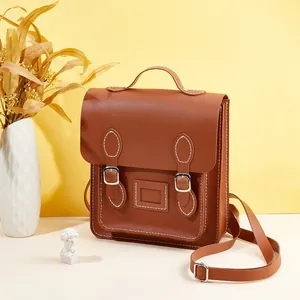 Detail of vintage brown leather satchel with dual buckle closure and white stitching decor