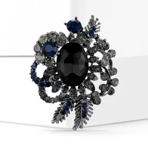 Macro view of vintage flower brooch featuring a black oval gem and blue rhinestones