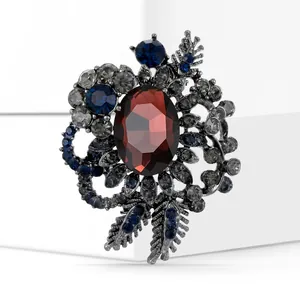 Detail of vintage flower brooch with deep red stone and blue crystals on gunmetal base