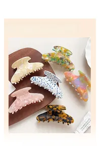 Detail of 6 colorful acetate hair claws showing marble and floral patterns texture