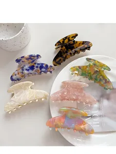 Flat lay of colorful acetate hair claws in various patterns on a minimalist white tray