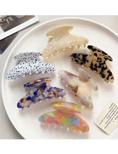 Top view of six colorful large acetate claw clips in a ceramic bowl with marble patterns