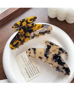 Macro detail of tortoiseshell and cream acetate hair claws in a ceramic dish