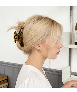 Macro view of a large tortoiseshell hair claw clip securing a chic updo hairstyle